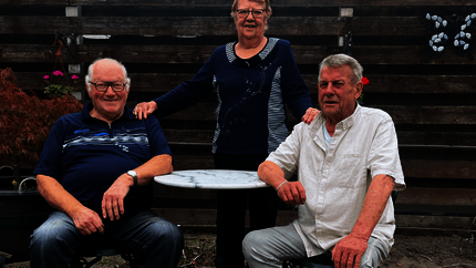 heer en mevrouw Smolders en heer Van Bakel. Mannen zitten aan een tafeltje buiten en mevrouw staat erachter.